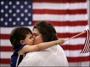 CTY flagday14p 03 - Cyndi Caron gets a big kiss fron her son Tristin, 3, at they listen to the Toledo Interfaith Mass Chior at the rally for the troops at the Lucas County Rec Center, as they bring the crowd to their feet with patriotic songs. The Blade/Allan Detrich