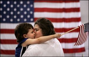 CTY flagday14p 03 - Cyndi Caron gets a big kiss fron her son Tristin, 3, at they listen to the Toledo Interfaith Mass Chior at the rally for the troops at the Lucas County Rec Center, as they bring the crowd to their feet with patriotic songs. The Blade/Allan Detrich