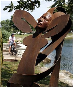Joel Lopez of Gibsonburg, in background, stops near 'Pardo Desnudo II,' a sculpture in Williams Park by Mike Sohikian.
