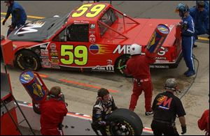 Crew members fuel Robert Pressley's truck during a pit stop yesterday at Michigan International Speedway.