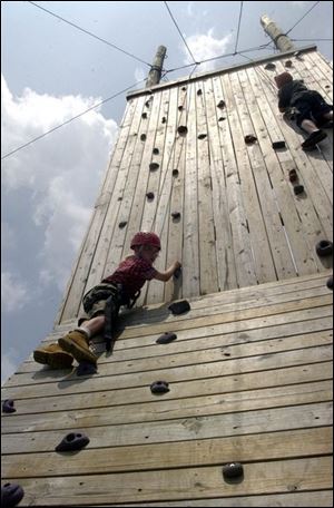 Eric Karr, 12, of Fremont, and Adam Rice, 12, of Monroe, Mich., scale the climbing wall at Camp Libbey in Defiance, Ohio.

