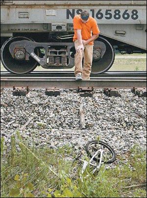Toledo Edison worker Nick Lyon pauses at the scene of an accident on Pemberville Road in which an 11-year-old Lake Township boy was killed by a train while riding his bicycle across the tracks. Mr. Lyon was first to reach the boy, who was pronounced dead at the scene. The incident occurred yesterday morning. 