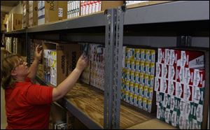 Tracy Scott, an employee at Barney's convenience store at Alexis Road and Detroit Avenue, restocks cigarettes on the store's shelves. Today, the cigarette tax will jump 70 cents per pack.