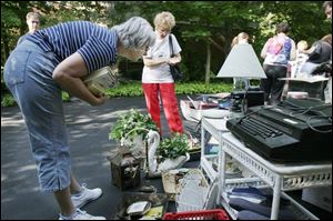 Jan Alexander of Pemberville, left, takes a close look at garage sale items in Perrysburg s Carrington Woods subdivision.