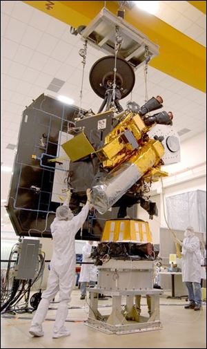 Workers prepare the Deep Impact flyby spacecraft and its impactor (bottom front) for its flight toward Comet Tempel 1.