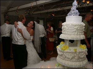 Bride Gretchen Burns dances with a wedding guest during the dollar dance at the reception. The cake is nearby, ready for cutting by the bride and her groom, Robert Burns.