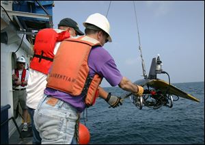 Andy Yehiela, left, and Nathan Hawley launch a Plankton Survey System from the Laurentian
during a research operation on Lake Erie near Cleveland.
