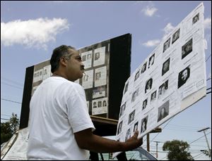 Felix DeJesus of Cleveland looks at photographs of missing children during a rally on Byrne Road. His teenage daughter, Georgina, vanished as she was walking home from school.