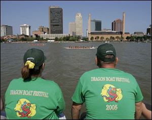 Jenny Bruns, left, and Joe Meyers, members of the Brooks Insurance Agency Coverage Crew team, watch one of the races during the Great Maumee River Dragon Boat Festival.