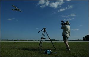 Jendra Jarnagin films an airplane flown by Shane Williams of Phoenix, as he tries to show how Christopher Malhoit's plane swept low to the ground before crashing on May 3, 1996, at the Fulton County Airport in Wauseon.