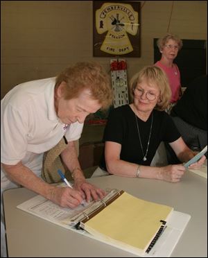 Gussie Oberhouse signs in to vote on the Eastwood school levy in Precinct 240 as poll worker Carol Moore looks on, at the
Pemberville fire house.