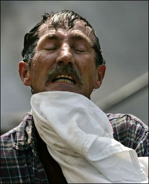 ROV Roofer Bob Helle wipes his face, after hosing himself down,  while he and co-workers were installing a new roof on the Health and Human Resources building at the University of Toledo on Tuesday, August 9, 2005.  Helle was operating the cold pitch tar kettle, which melts the material at a temperature of about 375 degrees, before it is pumped to the roof.  Helle is 47 years old, from Williston, O.  (They didn't want to give the name of their company.) The Blade/Dave Zapotosky