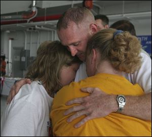 Ashley Wilburn, 12, David Lockert, and his sister, Pam Wilburn, hug during a farewell ceremony, above, for departing members of the 180th Fighter Wing of the Ohio Air National Guard. The unit, based at Toledo Express Airport, departed yesterday for the Mideast. 