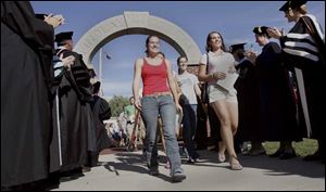 Freshmen stride through Griffith Memorial Arch as faculty members cheer them on.