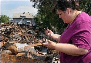 Claudia Vercellotti, a local coordinator of the Survivors Network of those Abused by Priests, examines some of the charred remains on the site where her residence once stood. Ms. Vercellotti told authorities that she left her home about 45 minutes before the blaze was reported by a passing city employee, who observed smoke wafting from between two homes.