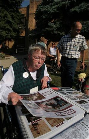 Jolynn Tyson, a member of Wood Lane s first class, looks over a scrapbook from the school.
