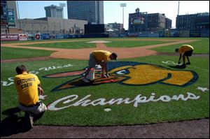 Fifth Third Field grounds crew members Jake Tyler, Matt Henn and Casey Myers paint the 2005 West Division Champions logo yesterday.