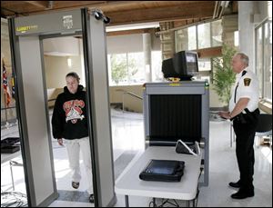 Carey Hofner of Bowling Green walks through a metal detector as Wood County constable Mac
McGillivray watches in a test of a security system at the county courthouse in May.
