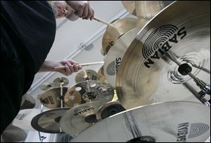 Gordon Sharpe of Addison, Mich, who plays in the band Secret
Weapons, tries some cymbals during the display and demonstration
by the Sabian cymbal-making company at Peeler
Music and Drum Center in Toledo.