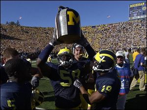 Michigan's Willis Barringer (19) and former linebacker Roy Manning hoist the Little Brown Jug following the Wolverines' 27-24 victory over Minnesota last season in Ann Arbor.