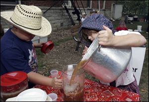 Katelyn Bennett, 10, right, pours freshly made apple cider into a pitcher being held by her brother, Garrett, 9, so they could pass out free samples. 