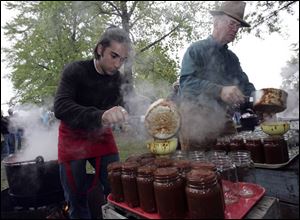 Brian Footer, left, of Athens, Ohio, and Steve Kryder of McClure, Ohio, pour apple butter into jars at Grand Rapids' 29th annual apple butter fesitval. The lines to get jars were more than 100 people deep.