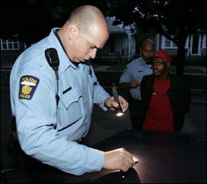 Officer Mickey Mitchcell, foreground, and his partner, Officer Furr. arrest Ollie Haynes, 60, near Dorr Street, accusing him of possessing drugs.