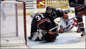 The Storm's Jeff Attard keeps his focus and puts the puck past goalie Mike Ayers despite being decked by Alex Johnstone.