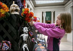 Edie Buess Dickinson of Bowling Green puts a hand-made flower on the altar during the Day of the Dead celebration at the Toledo Museum of Art yesterday.