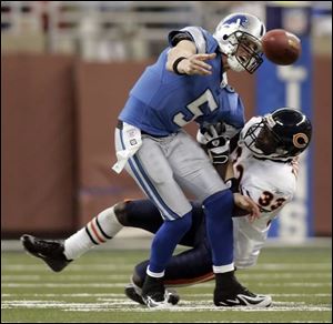 Lions quarterback Jeff Garcia tosses the ball to a teammate as he is tackled by Charles Tillman.