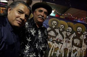DAY OF THE DEAD: Joe Balderas, left, and Joe Lopez stand near Mr. Lopez' painting, <i>Day of the Dead</i>, at the Sofia Quintero Art and Cultural Center. 
