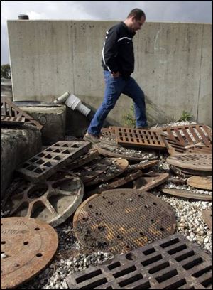 Sewer department foreman Bill Wiciak steps between sewer grates. About 122 such grates have been plucked from city streets, many in West Toledo, during the last four months.
