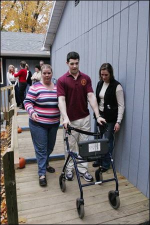 Former Army Spec. 4 Matthew Drake, injured in Iraq, uses a ramp at his renovated Sylvania home, escorted by health-care assistant Christine Anderson, left, and Treca Zyback.