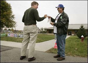John Pristash, left, takes a sticker from Gary Munch outside the Sylvania Senior Center on Sylvania Avenue yesterday.