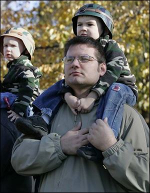 Donald James Wensinger IV, 3, sits on the shoulders of his father, Donald James Wensinger III, in a Fremont ceremony.