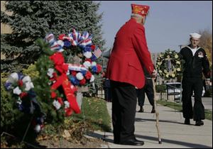 Veteran Mike Leitner, a member of the Military Order of the Cooties, Pup Tent 4, watches SK2/SS Keith Pasenow carry a wreath to a monument. 