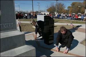 Larry Luersman and Greg Feathers place engraved bricks in Delphos' new veterans memorial at Fifth and Main streets. A local foundation helped pay for the $157,000 memorial.