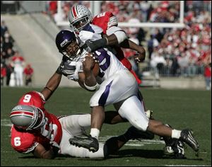 Northwestern running back Tyrell Sutton is dragged down by Ohio State senior cornerback Tyler Everett (6) and senior safety Nate Salley. Yesterday's home game was the last home game for 16 Buckeye seniors. Sutton, a freshman from Akron who was Ohio's Mr. Football last year, had 93 yards on 14 carries.