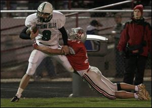 Senior tight end Adam Tansey (9) of Ottawa Hills is dragged out of bounds by Hopewell-Loudon's Sean Brickner last night at Fostoria Memorial Stadium.