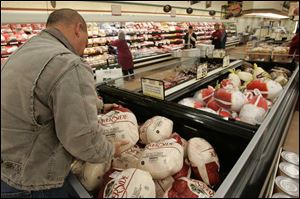 John Glass selects a frozen turkey from the promotional brand at Kroger on Suder Avenue. 