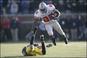 OSU running back Antonio Pittman leaps over Michigan's Morgan Trent for a first down in the fourth quarter.