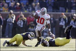 Ohio State's Troy Smith slips between Michigan's Morgan Trent, left, and Alan Branch for first down. The junior quarterback, who completed 27 of 37 passes for 300 yards, led the Buckeyes to their second straight win over the Wolverines and their fourth win in five years against UM.