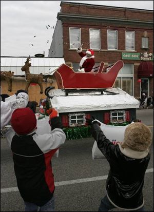 Children hold up their bags for catching or gathering candy tossed during the East Toledo Christmas Parade.