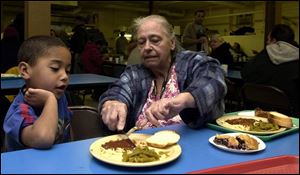 Kenny Johnson, 4, and his great-grandmother, Joyce Doss, eat at the Helping Hands of St. Louis soup kitchen in East Toledo. Ms. Doss takes him there to ensure he gets a hot meal because her Social Security check often isn't enough to make ends meet.