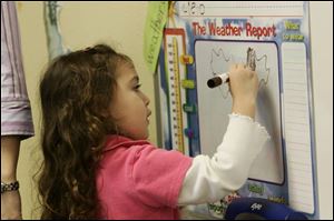 Kindergartner Cielo Caputo, 5, makes out the weather report for her classmates at Wildwood Environmental; Academy, which has students from kindergarten through eighth grade. Wildwood has not been open long enough for a state rating but reports that test scores among students tested last year have been encouraging.