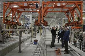 Plant officials, from left, Steve Azoni, Ted Roberts, and Dave Elshoff examine part of a new addition at Toledo Jeep Assembly, where new Wranglers will undergo final assembly.