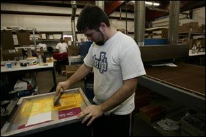 Jon Iwinski silk-screens the yellow onto University of Toledo GMAC Bowl T-shirts at Team Sports Inc.