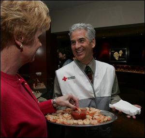MAY I BE OF SERVICE: Nancy Howenstein takes a helping of shrimp from Don Baker during the Red Cross kickoff party at Harold Jaffe Jewelers.