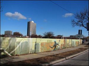 The Spirit of Detroit sculpture is featured in a printed fence surrounding a construction site.