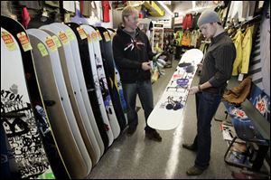 Mark Musgrave, left, manager of Red Sky Surf & Snow, helps Fernando Lopez consider a snowboard. 